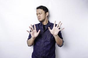 bonito homem asiático vestindo camisa azul com pose de gesto de mão de parada ou proibição com espaço de cópia foto