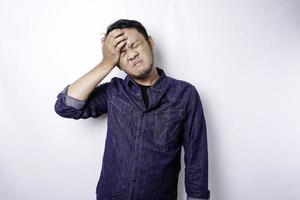 um retrato de um homem asiático vestindo uma camisa azul isolada por um fundo branco parece deprimido foto