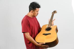retrato de jovem asiático em camiseta vermelha com um violão isolado no fundo branco foto