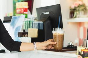 mulher segurando o copo plástico para viagem de café gelado no café. foto