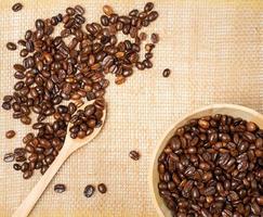 grãos de café torrados estão prontos para moer em uma mesa de madeira foto