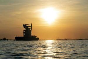 silos de grãos descarregando navio ao pôr do sol na lagoa de veneza chioggia harbour foto