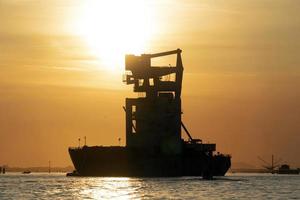 silos de grãos descarregando navio ao pôr do sol na lagoa de veneza chioggia harbour foto