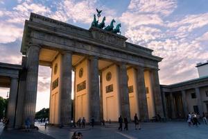 berlim, alemanha-8 de agosto de 2022-pessoas e turistas passeiam na pariser platz em frente ao portão de brandeburg durante o pôr do sol foto