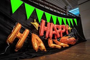 letras de balão laranja feliz dia das bruxas são preparadas no 2º andar para pendurar no terraço com bandeira de abóbora e fundo de pano preto no evento de festa de halloween. foto