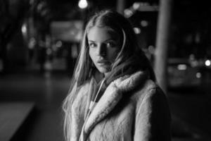 retrato preto e branco de uma garota contra o fundo de uma cidade noturna foto