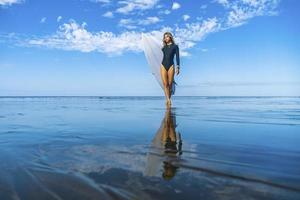 mulher jovem e atlética com sua prancha de surf na praia foto