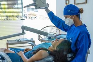 dentista em máscara e jaleco examina um paciente. foto