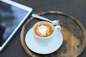 café quente na mesa pronto para ser comido. há um computador e um telefone para o trabalho. foto