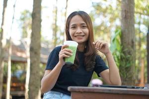 as mulheres asiáticas ficam felizes em sentar e trabalhar em uma cafeteria. há árvores verdes cercadas pela natureza. planejamento de negócios é uma boa ideia. foto