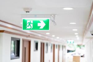 um sinal de caixa de luz de seta de saída de incêndio de emergência é pendurado no teto na passarela do hospital, ideia para exercícios de incêndio ou evacuação de eventos. foto
