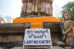 fique na frente de phra that chom kitti. a letra tailandesa azul no quadro branco significa senhora não entra, um local de culto em chiang rai, tailândia. foto