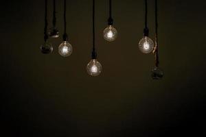 feche um grupo de lâmpadas de tungstênio clássicas penduradas na área escura com corda. foto