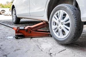 feche até a fixação do pneu quebrado com carro branco na garagem local da tailândia. foto