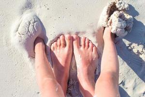 closeup mãe e pés de criança na praia de areia branca foto