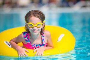 menina com círculo de borracha inflável se divertindo na piscina ao ar livre foto