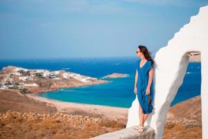 jovem e tradicional igreja branca com vista para o mar na ilha de mykonos, grécia foto