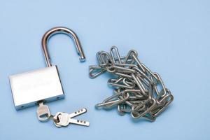 cadeado aberto com chaves e corrente no fundo azul foto