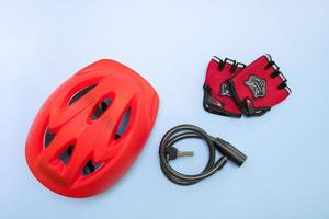 capacete de bicicleta, cadeado com chaves e luvas em um fundo azul foto