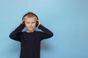 menino em fones de ouvido em um fundo azul com espaço de cópia foto