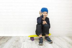 menino sentado em um skate e falando ao telefone foto