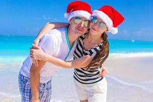 retrato de jovem casal de chapéu de Papai Noel curtir férias de praia foto