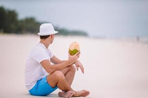 jovem bebendo leite de coco durante as férias tropicais foto