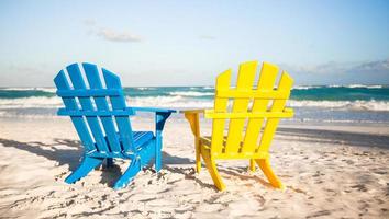 duas cadeiras de madeira, amarelas e azuis em uma praia de areia branca, méxico foto