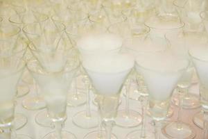 detalhes de taças de champanhe. gelo seco em arranjos de vidro para recepção de casamento foto