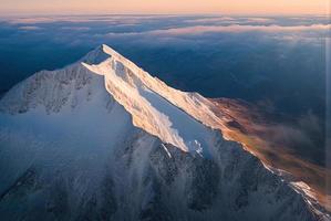 tiro de foto de paisagem aérea de uma montanha de cima, névoa e neve