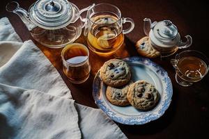 fotografia de um prato de biscoitos e um copo de chá sobre uma mesa com uma toalha e um guardanapo sobre ela foto