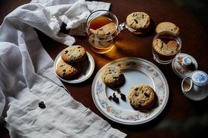 fotografia de um prato de biscoitos e um copo de chá sobre uma mesa com uma toalha e um guardanapo sobre ela foto