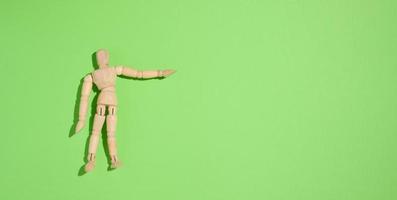 homem fantoche de madeira sobre um fundo verde, apontando com a mão foto