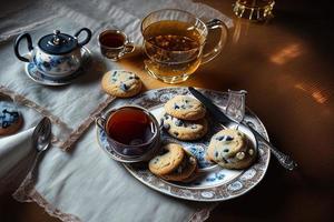 fotografia de um prato de biscoitos e um copo de chá sobre uma mesa com uma toalha e um guardanapo sobre ela foto