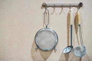 utensílios de cozinha em prateleiras de aço. espátulas de aço etc. contra parede de madeira rústica com espaço de cópia foto
