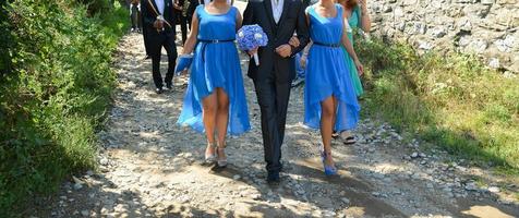 casamento tradicional romeno. noivo junto com as damas de honra estão caminhando pelas estradas da vila foto