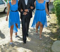 casamento tradicional romeno. noivo junto com as damas de honra estão caminhando pelas estradas da vila foto