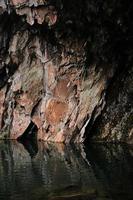 formação de rocha marrom e cinza ao lado do corpo d'água durante o dia