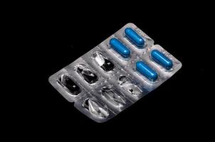 pílulas azuis em fundo preto foto