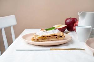 pedaço caseiro de torta de maçã com maçãs vermelhas frescas na mesa branca foto