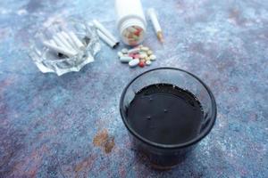 álcool, pílulas e cigarro na mesa foto