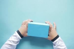 vista superior da mão da criança segurando uma caixa de presente de cor azul foto