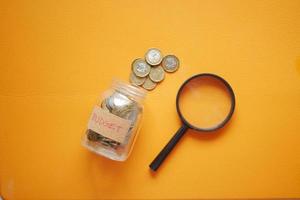 texto de orçamento em uma jarra de moedas de poupança em branco foto