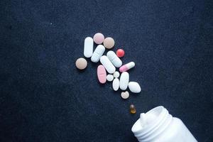 close-up de muitos comprimidos e cápsulas coloridas em fundo preto foto