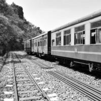 trem de brinquedo movendo-se na encosta da montanha, bela vista, uma montanha lateral, um vale lateral movendo-se na ferrovia para a colina, entre a floresta natural verde. trem de brinquedo de kalka para shimla na índia foto