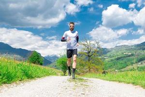 corredor de maratona treina em uma estrada de terra de montanha foto