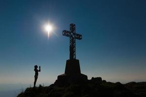 menina reza em frente à montanha até a cruz do cume foto