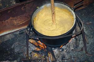 polenta de preparação sobre um fogo de lenha foto