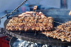 cozinhar churrasco de frango na cesta de churrasco com cabo de madeira, fumaça deliciosa e espessa foto