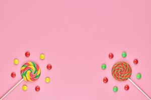 pirulitos doces e doces no fundo rosa foto